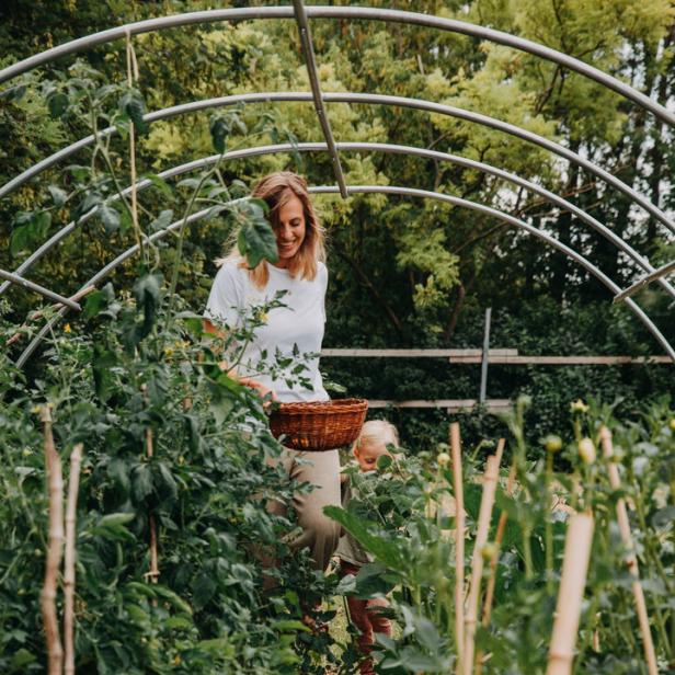 Eine Frau und ein Kind stehen in einem Gemüsegarten mit Tomatenpflanzen.