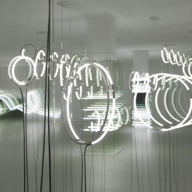 Kreisförmige Neonröhren hängen von der Decke und bilden eine Installation.