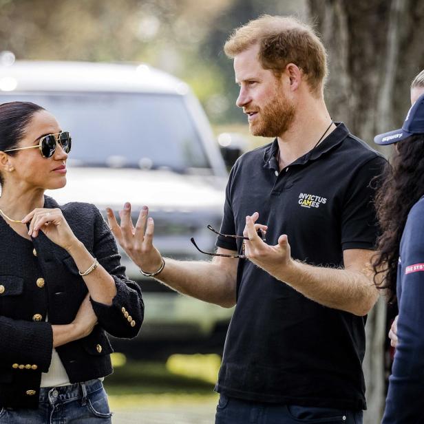 Prinz Harry und Meghan Markle unterhalten sich im Freien.