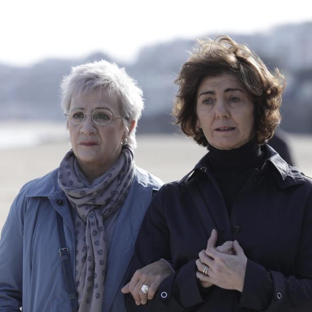 Zwei Frauen mittleren Alters gehen am Strand spazieren.