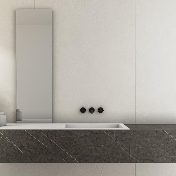 Ein modernes Badezimmer mit einem Waschtisch aus Marmor und einem hohen Spiegel.