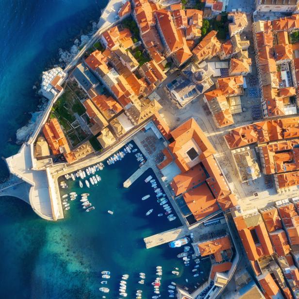 Luftaufnahme von Dubrovnik, Kroatien, mit roten Dächern und einem Hafen voller Boote.