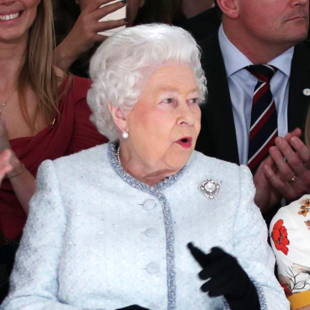 Königin Elisabeth II. in einem hellblauen Kostüm und schwarzen Handschuhen.