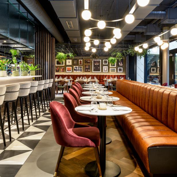Innenansicht eines eleganten Restaurants mit Bar und Tischen.