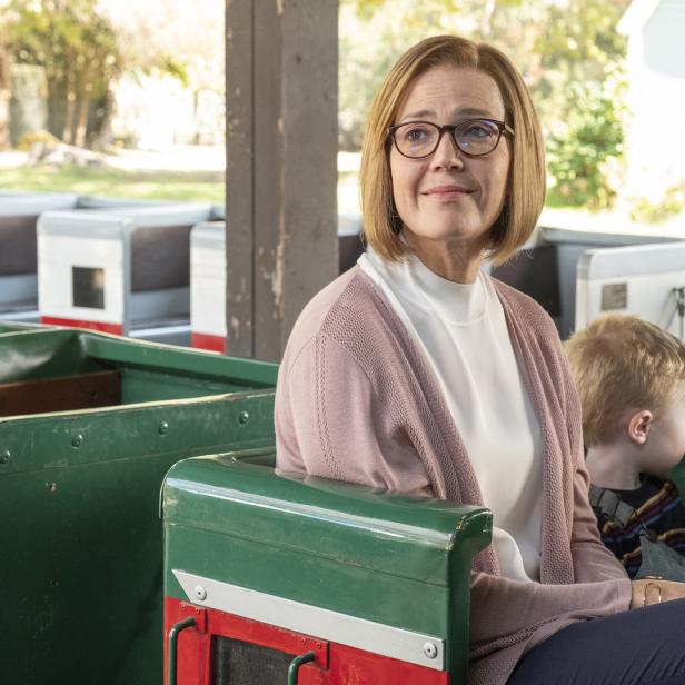 Eine Frau mit Brille und ein Kind sitzen in einem grünen Zug.