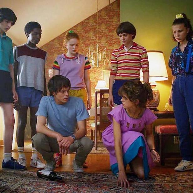 Die jugendlichen Hauptdarsteller der Serie „Stranger Things“ stehen in einem Wohnzimmer.