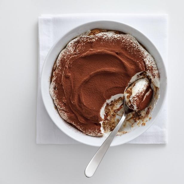 Ein Tiramisu in einer weißen Schüssel mit einem Löffel darin.