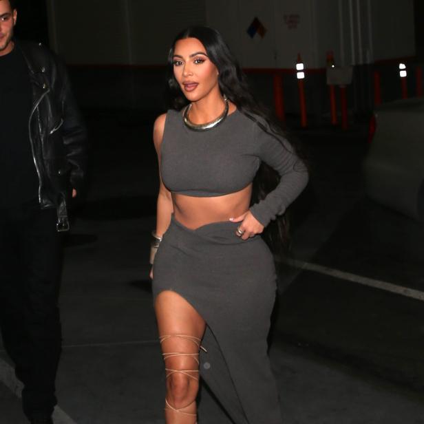 Kim Kardashian trägt ein graues zweiteiliges Outfit und Schnürschuhe.