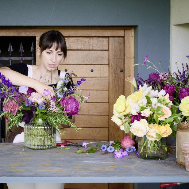 Eine Frau arrangiert Blumen in einer Vase.
