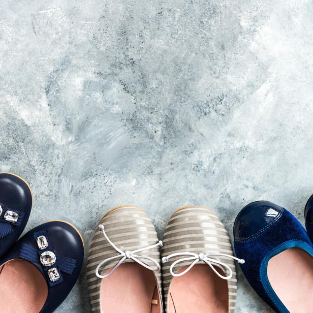 Mehrere Paar Ballerinas stehen auf einem grauen Hintergrund.