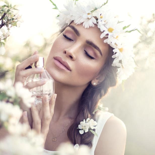 Eine Frau mit Blumenkranz sprüht sich Parfüm auf.