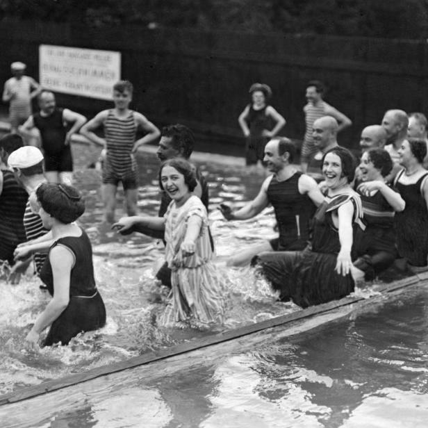 Eine Gruppe von Menschen in Badebekleidung vergnügt sich im Wasser.