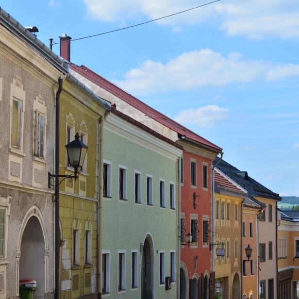 Eine Reihe farbenfroher Häuser in einer europäischen Stadt unter blauem Himmel.