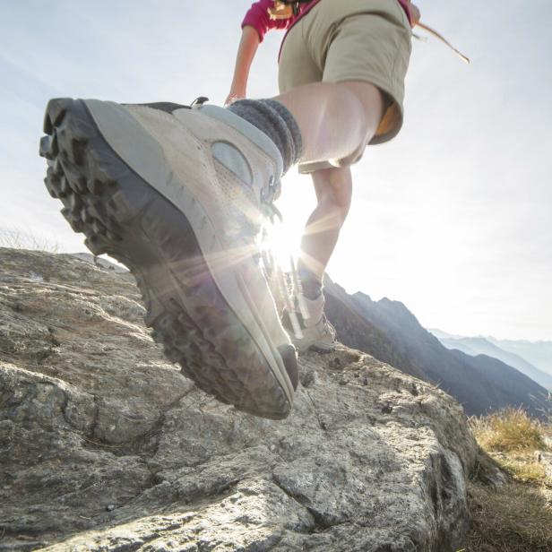 Wanderschuhe in Großaufnahme steigen über einen felsigen Pfad.