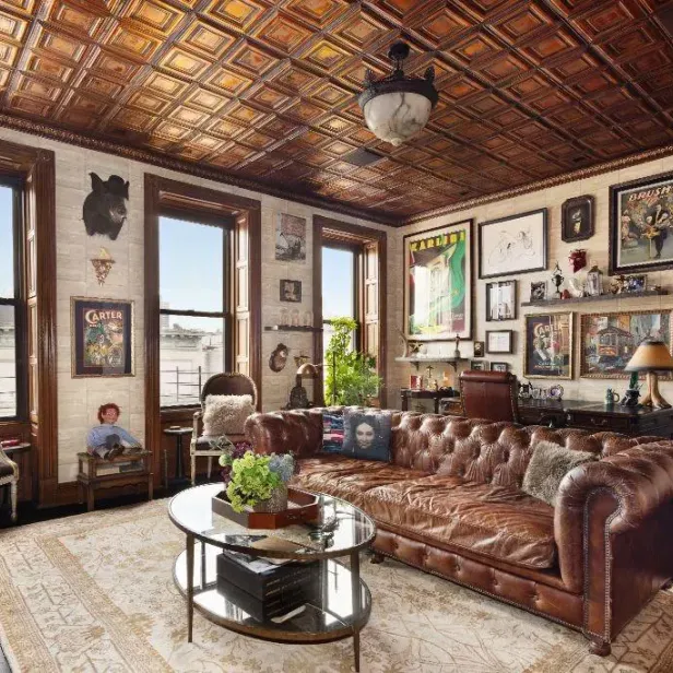 Ein Wohnzimmer mit einem braunen Ledersofa und vielen Bildern an der Wand.