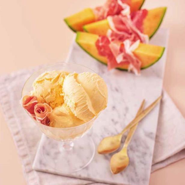 Ein Glas Meloneneis mit Schinkenröschen und Melonenspalten mit Schinken belegt.