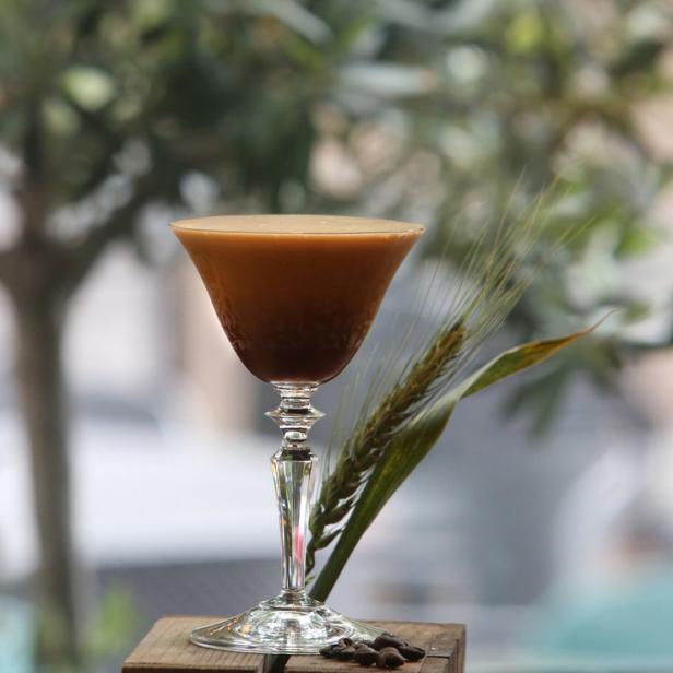 Ein Espresso Martini in einem eleganten Glas, garniert mit einem Weizenhalm.