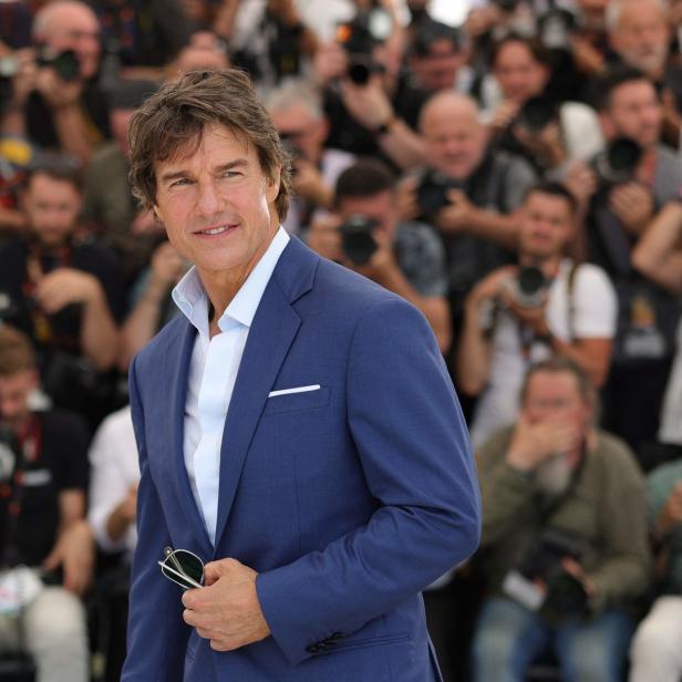 Tom Cruise posiert vor einer Menschenmenge mit Kameras.
