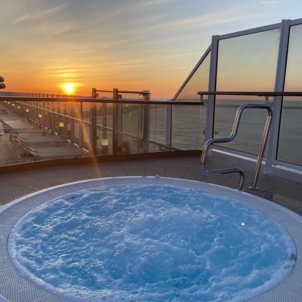 Ein sprudelnder Whirlpool auf einem Schiff mit Blick auf den Sonnenuntergang.