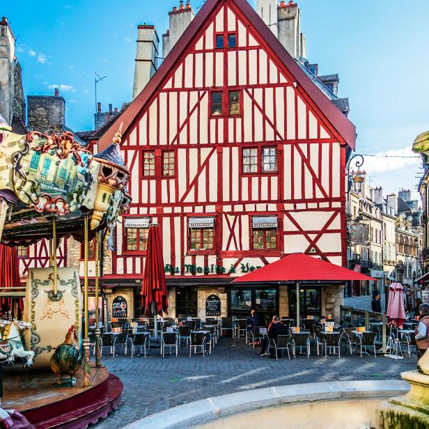 Ein Karussell und ein Restaurant mit rotem Fachwerk auf einem belebten Platz.