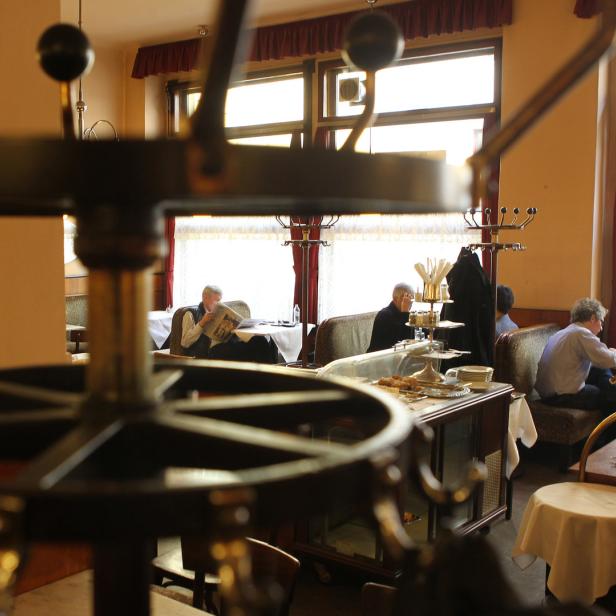Mehrere Personen sitzen in einem traditionellen Wiener Kaffeehaus.
