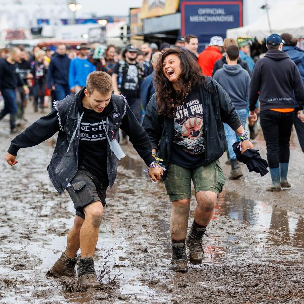 Besucher laufen schlammbedeckt beim Nova Rock Festival 2022.