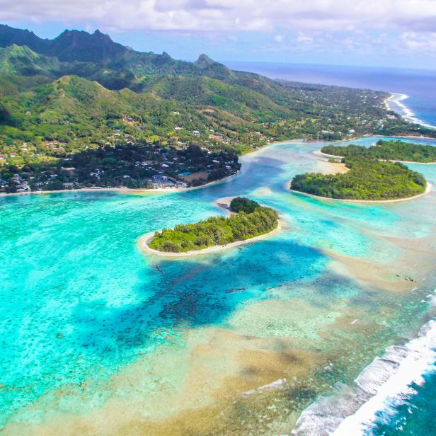 Luftaufnahme einer tropischen Insel mit türkisfarbenem Wasser und üppiger Vegetation.