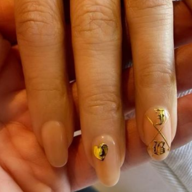 Nahaufnahme von lackierten Fingernägeln mit goldenen Verzierungen.