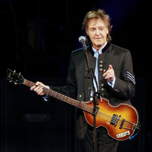 Paul McCartney spielt auf der Bühne Bassgitarre.