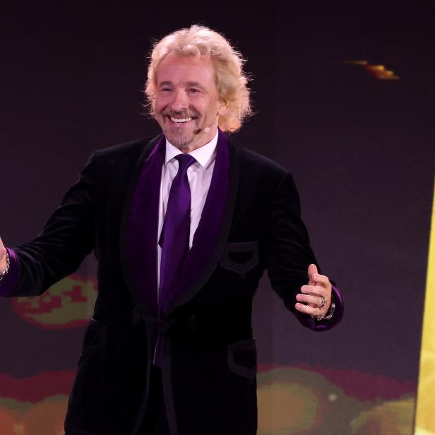 Thomas Gottschalk moderiert eine Veranstaltung vor dem Schriftzug „2021“.