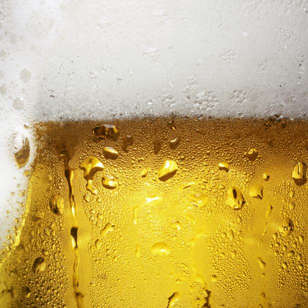 Nahaufnahme eines Glases mit hellem Bier und Schaumkrone, bedeckt mit Kondenswasser.