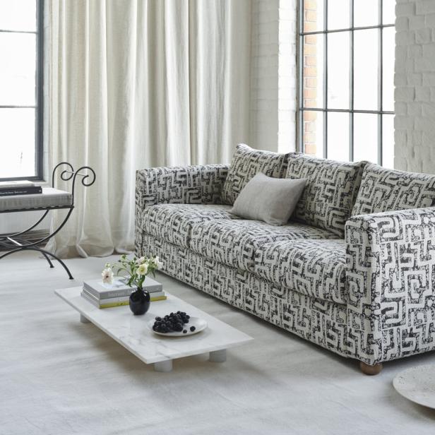 Ein Sofa mit geometrischem Muster steht in einem hellen Wohnzimmer.