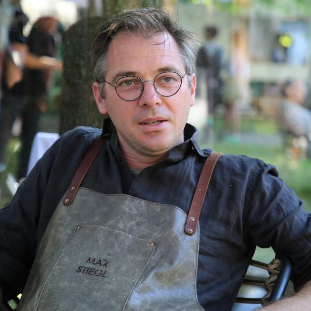 Max Stiegl sitzt mit einer Lederschürze in einem Garten.