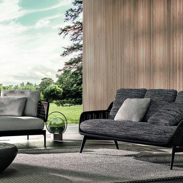 Zwei moderne Sofas stehen auf einer Terrasse mit Blick auf eine grüne Landschaft.