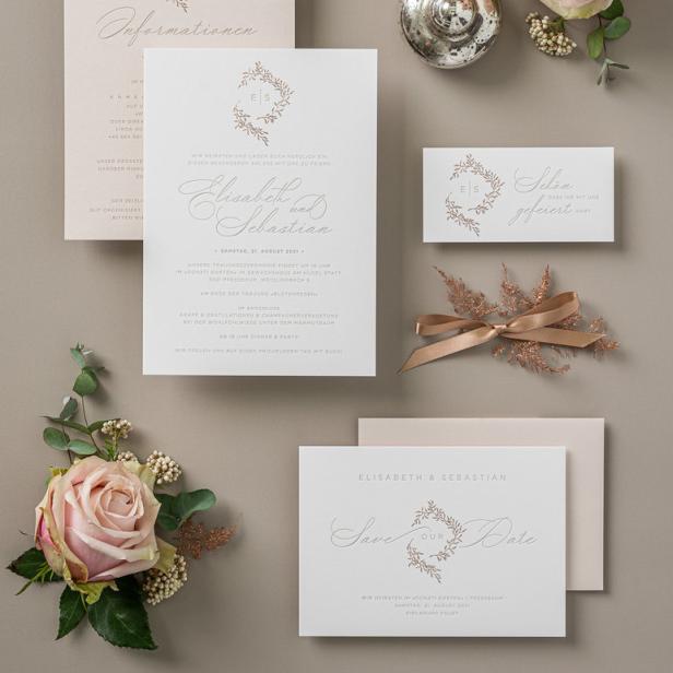 Hochzeitseinladungen mit rosa Rosen und dekorativen Elementen auf einem Tisch arrangiert.