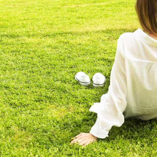 Eine Frau liegt im Gras, ihre weißen Turnschuhe stehen daneben.