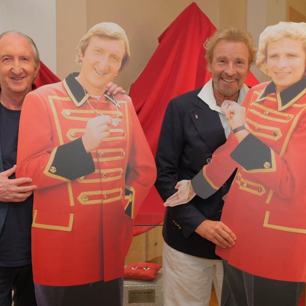 Zwei Männer posieren mit Pappaufstellern von Thomas Gottschalk in roter Uniform.