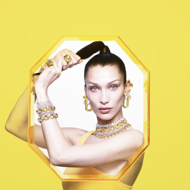 Bella Hadid präsentiert gelben Schmuck vor einem gelben Hintergrund.