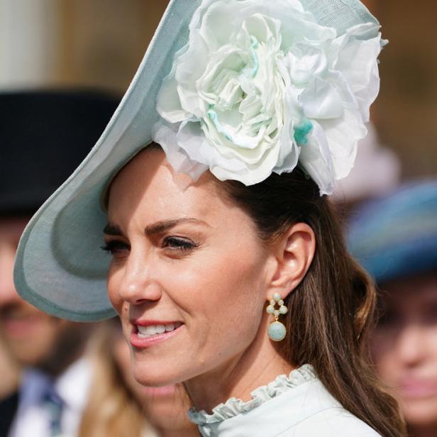 Kate Middleton mit einem hellblauen Hut mit einer großen weißen Blume.