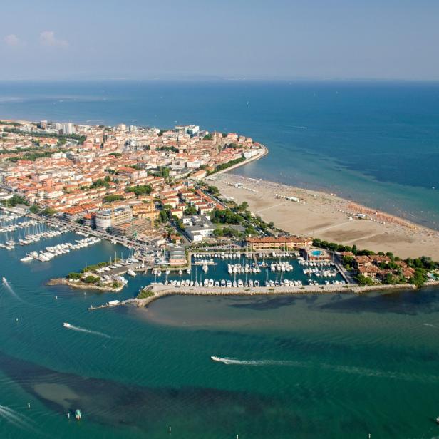 Luftaufnahme von Grado, Italien, mit Blick auf die Stadt, den Strand und den Hafen.