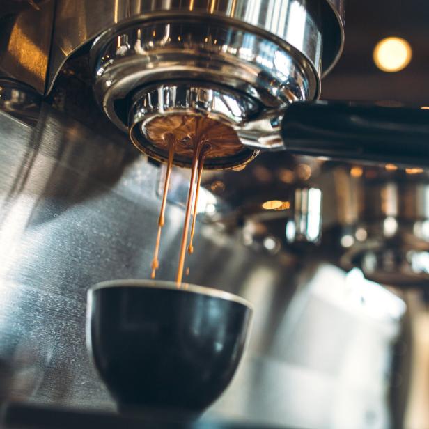 Espresso läuft aus einer professionellen Kaffeemaschine in eine Tasse.