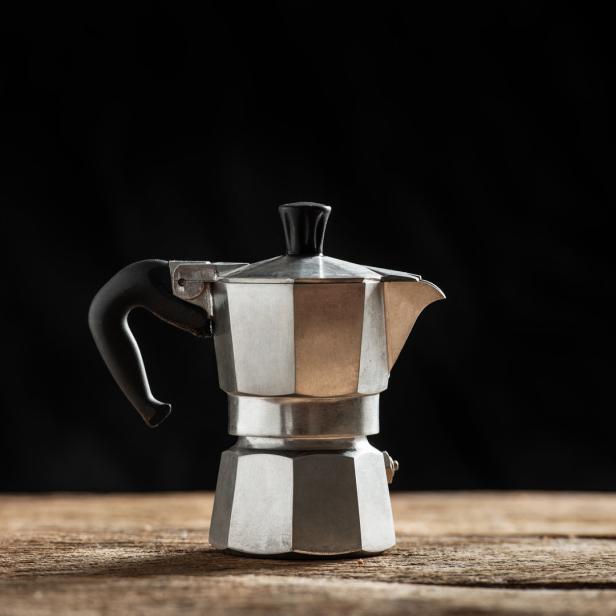 Eine silberne Espressokanne steht auf einem Holztisch.