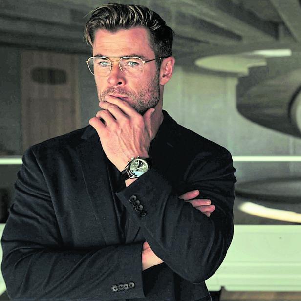 Chris Hemsworth steht in einem modernen Raum mit einer Wendeltreppe.