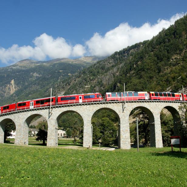 Ein roter Zug fährt über den Kreisviadukt Brusio in der Schweiz.