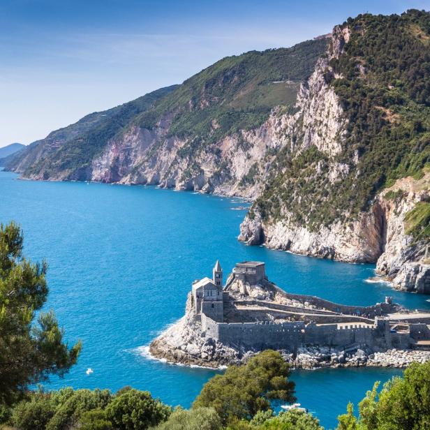 Blick auf die Kirche San Pietro in Porto Venere, Italien, umgeben von blauem Meer und felsiger Küste.