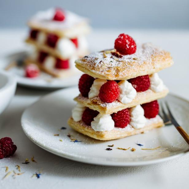 Ein Mille-Feuille mit Himbeeren und Schlagsahne auf einem Teller.