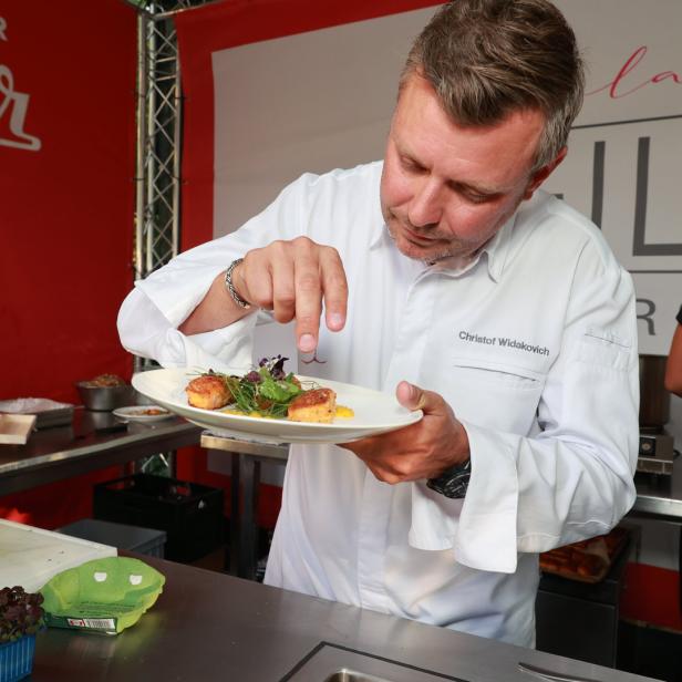 Christof Widakovich garniert ein Gericht mit Jakobsmuscheln und Salat.