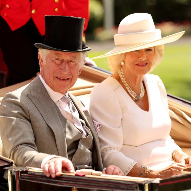 König Charles III. und Königin Camilla fahren in einer Kutsche.
