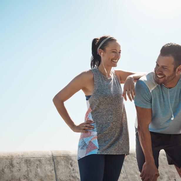 Eine Frau und ein Mann machen eine Pause vom Sport und unterhalten sich lachend.