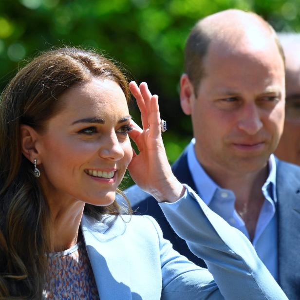 Catherine, Princess of Wales, lächelt mit Prinz William im Hintergrund.